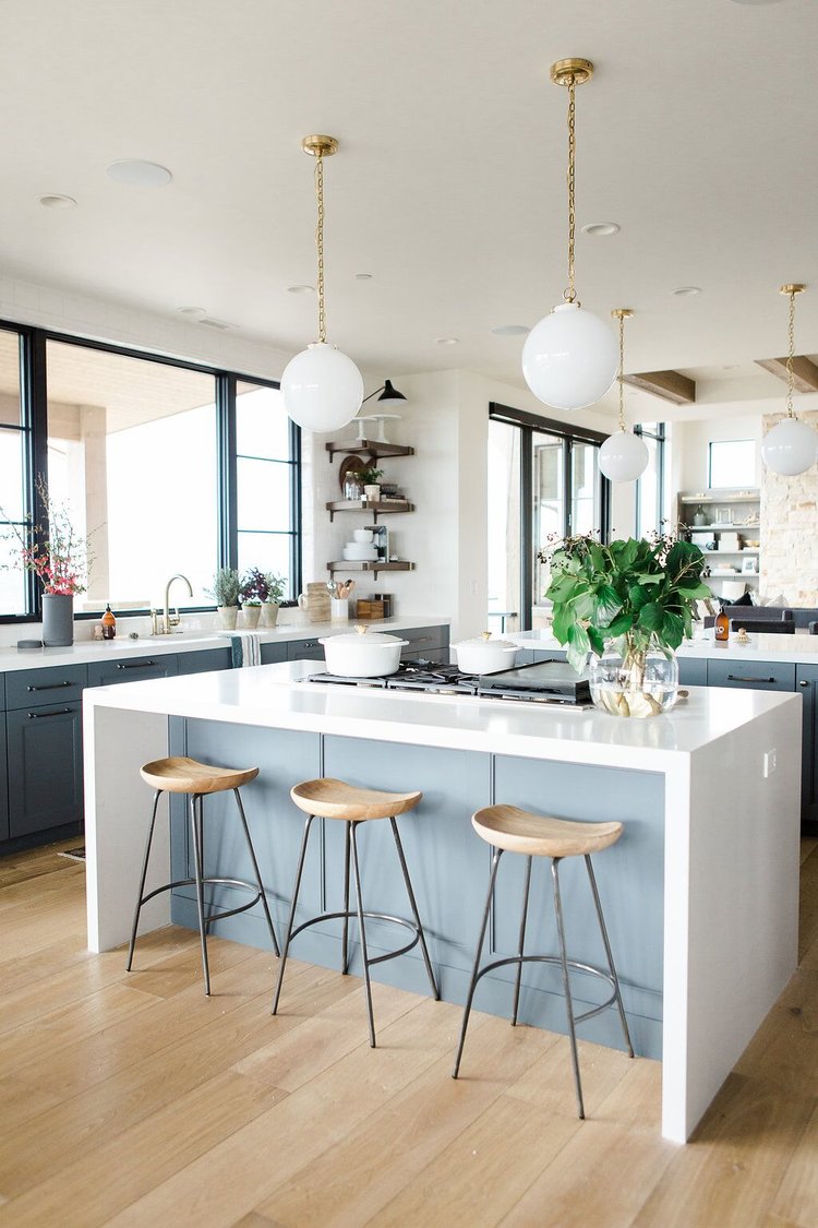 25Modern+kitchen+with+open+shelves,+natural+wood+barstools,+blue+cabinets+with+white+waterfall+edged+countertops
