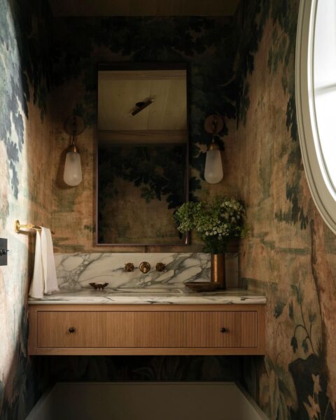 powder room with marble counter round window and wallpaper mural